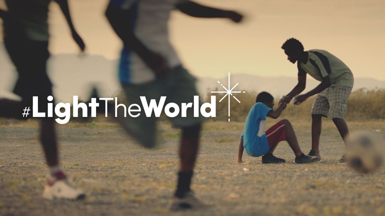 Un niño ayuda a otro a levantarse después de que se haya caído jugando al fútbol, en un vídeo de Ilumina el Mundo