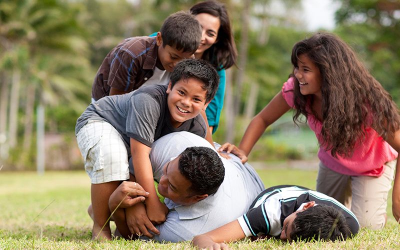 Una familia juega al fútbol en un parque viviendo la Palabra de Sabiduría
