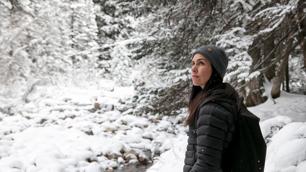 Una mujer camina por un bosque nevado