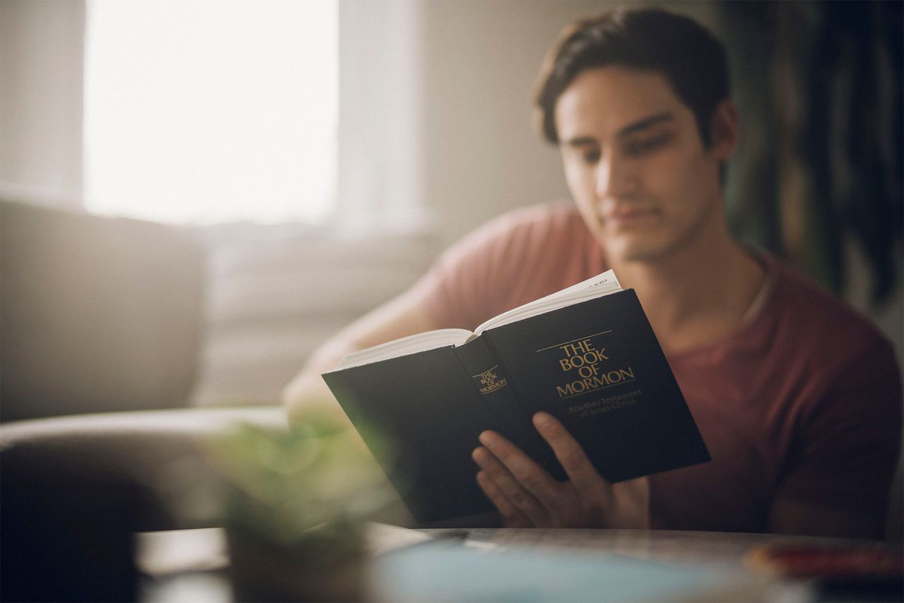 Un hombre estudia el Libro de Mormón en la mesa de la cocina