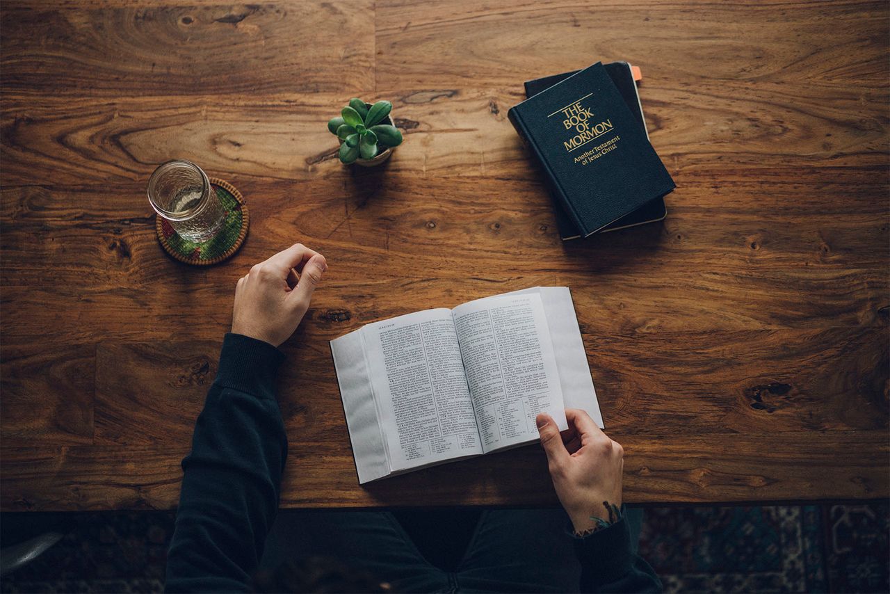 Un hombre estudia la Biblia y el Libro de Mormón en la mesa de la cocina