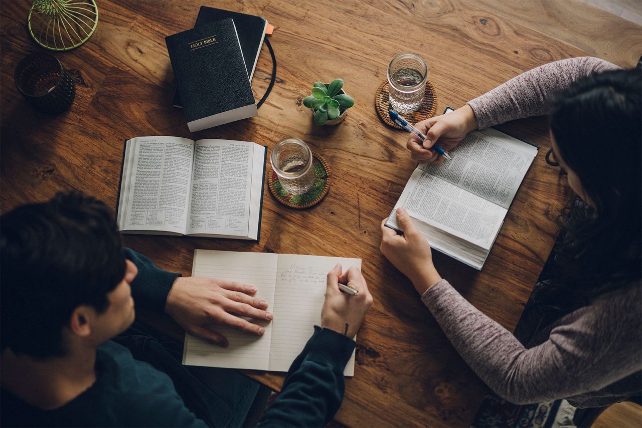 Dos personas se sientan juntas a la mesa de la cocina mientras estudian el mensaje que Dios tiene para ellas